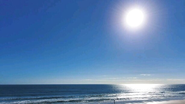 A beach with a clear sky and the sun shining over the ocean. - Brand New Pool on Daytona Beach!! (Daytona Beach)