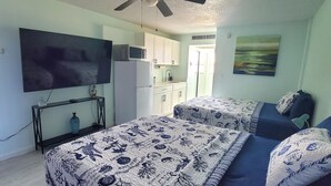 A bedroom with a bed, a TV, a ceiling fan, and a kitchenette. - Brand New Pool on Daytona Beach!! (Daytona Beach)