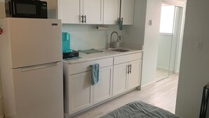 A compact kitchen with a refrigerator, a coffee maker, a sink, and cabinets. - Brand New Pool on Daytona Beach!! (Daytona Beach)