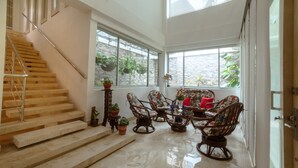 A spacious living area with a staircase, a dining table with chairs, and large windows with plants. - LUXURY HOUSE, CLOSE TO THE BEACH (Manzanillo del Mar)