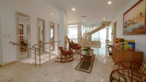 A spacious living area with a staircase, wicker furniture, and a large mirror. - LUXURY HOUSE, CLOSE TO THE BEACH (Manzanillo del Mar)