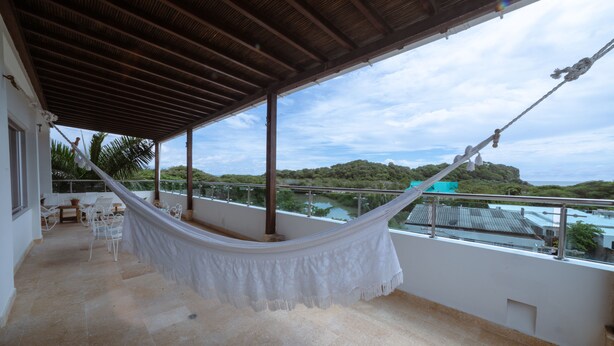 A balcony with a hammock, outdoor furniture, and a view of a hill and water. - LUXURY HOUSE, CLOSE TO THE BEACH (Manzanillo del Mar)