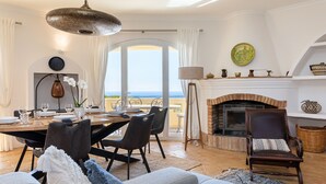 A dining area with a table set for six, a fireplace, and a view of the sea. - A perfect house on the right place with a unique and distinctive location (Faro)