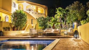 A pool area with a tiled pool, outdoor seating, and a staircase leading to a building with balconies. - A perfect house on the right place with a unique and distinctive location (Faro)