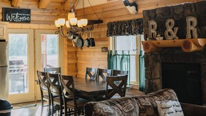 Un interior de madera con zona de comedor, chimenea y astas decorando la pared.