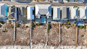 An aerial view of a coastal hotel with multiple buildings, a swimming pool, and a sandy beach. - Beachfront Daze, Oceanfront with Pool (Carolina Beach)