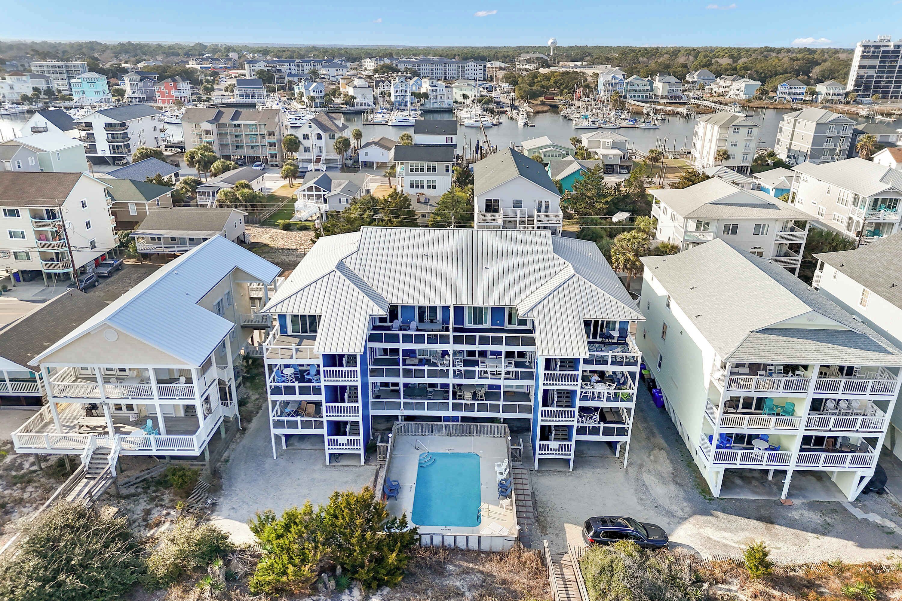 A multi-story hotel with a pool, located in a coastal town.