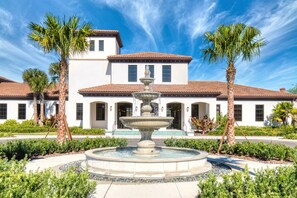 Stunning outdoor oasis with a central fountain surrounded by lush greenery and a charming two-story building.