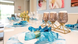 Une table dressée avec des serviettes, des assiettes et des verres bleus, ainsi que des objets de décoration en verre disposés sur des présentoirs.