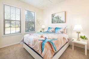 Relax in a serene bedroom with a large bed, framed artwork, and a bedside table.