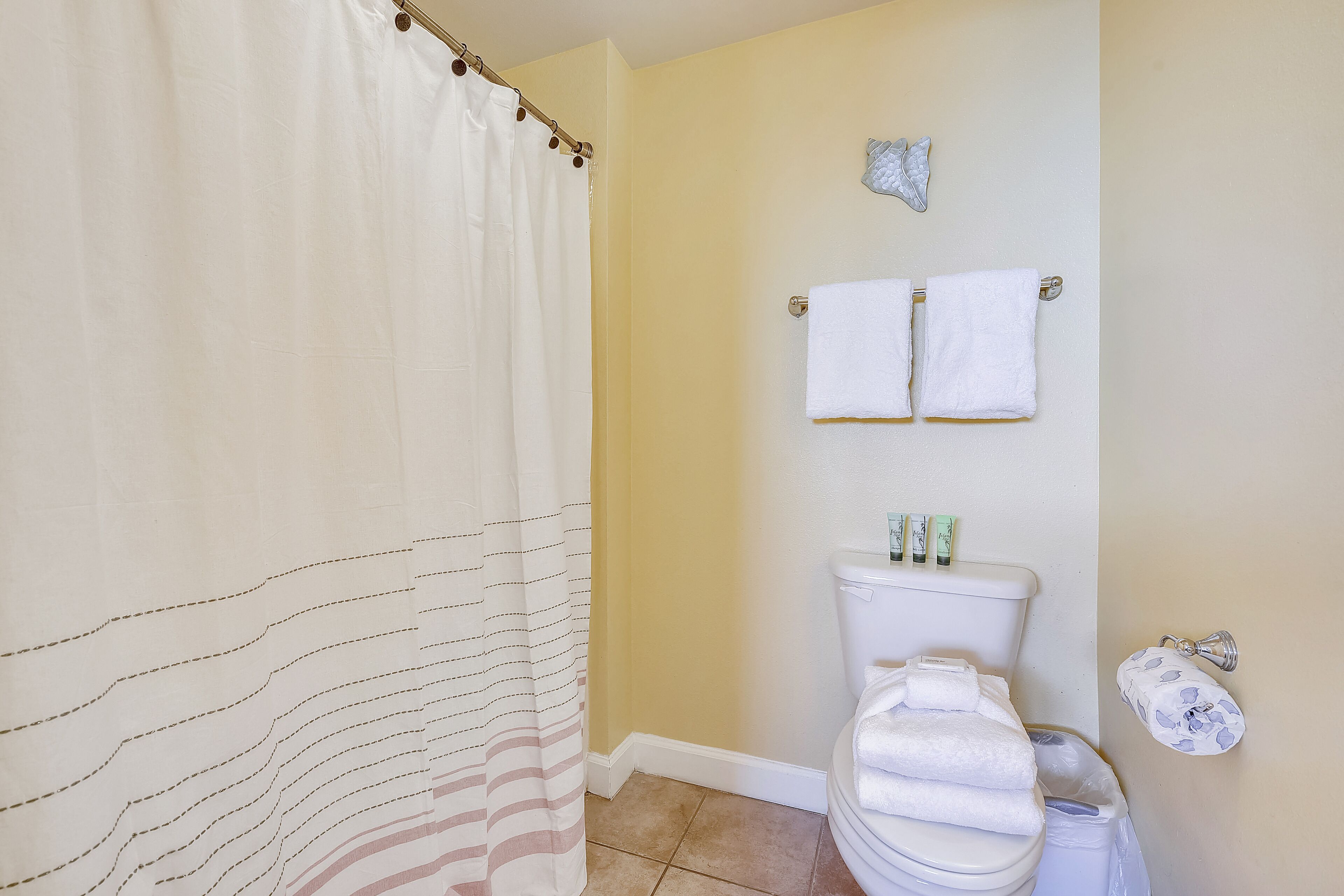 Un baño con cortina de ducha, un inodoro y dos toallas colgadas en la pared.