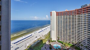 Un hotel moderno con vista a la playa, piscina y una carretera que lleva a la orilla.