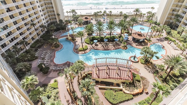 Un resort con varias piscinas, palmeras y vista al océano.