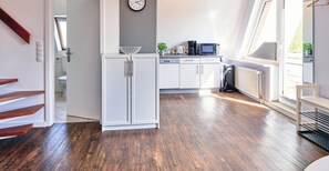 A modern kitchen with white cabinets, a clock, and a window.