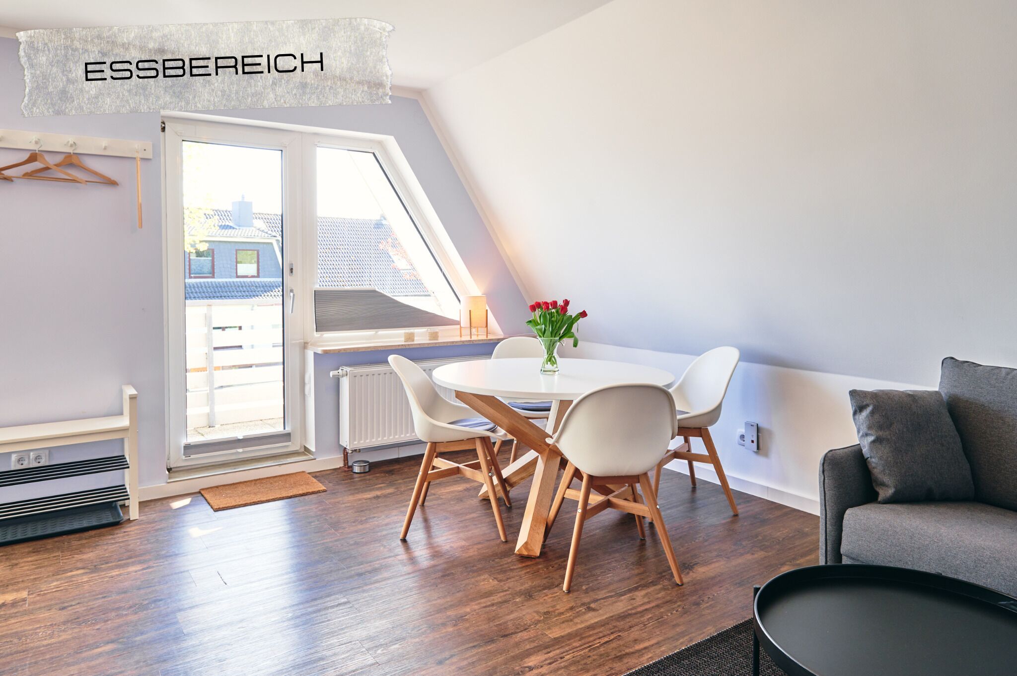 A modern room with a dining table, chairs, a sofa, and a radiator.