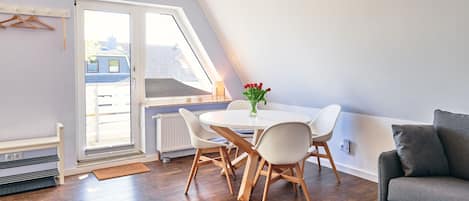 A modern room with a dining table, chairs, a sofa, and a radiator.