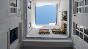 Ein schmaler Gang mit einem kleinen Fenster am Ende, der zu einem Balkon mit Blumentöpfen führt.
