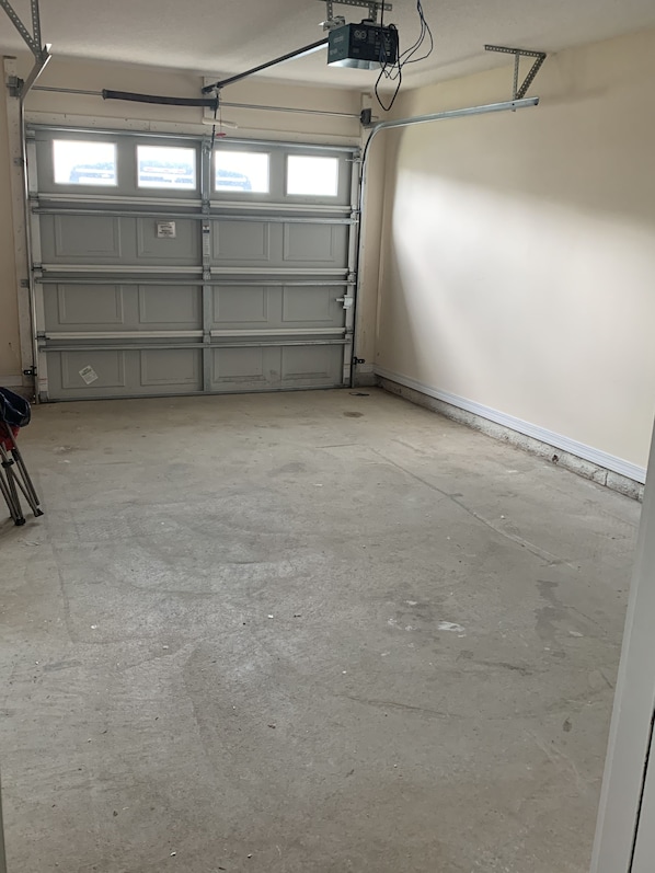 A garage with a closed garage door, concrete floor, and a ceiling-mounted projector.