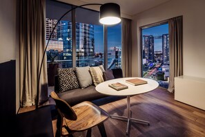 A modern living room with a sofa, a round table, and a view of a cityscape through large windows. - SLS Buenos Aires Puerto Madero (Buenos Aires)