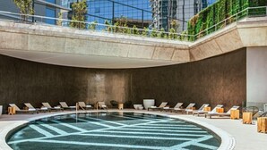 A modern indoor pool with a geometric pattern on the floor, surrounded by lounge chairs and sun loungers. - SLS Buenos Aires Puerto Madero (Buenos Aires)