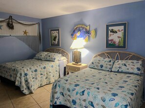 A room with two beds, a wall-mounted fish decoration, and a framed picture.