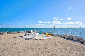 A pebbled beach with chairs and a flagpole.