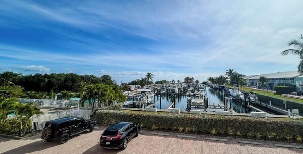 A marina with boats docked, a paved walkway, and a building in the background.