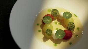 A white plate with a dessert featuring spherical shapes and green garnishes.