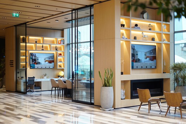 A modern lobby with a reception desk, seating area, and a TV mounted on the wall.