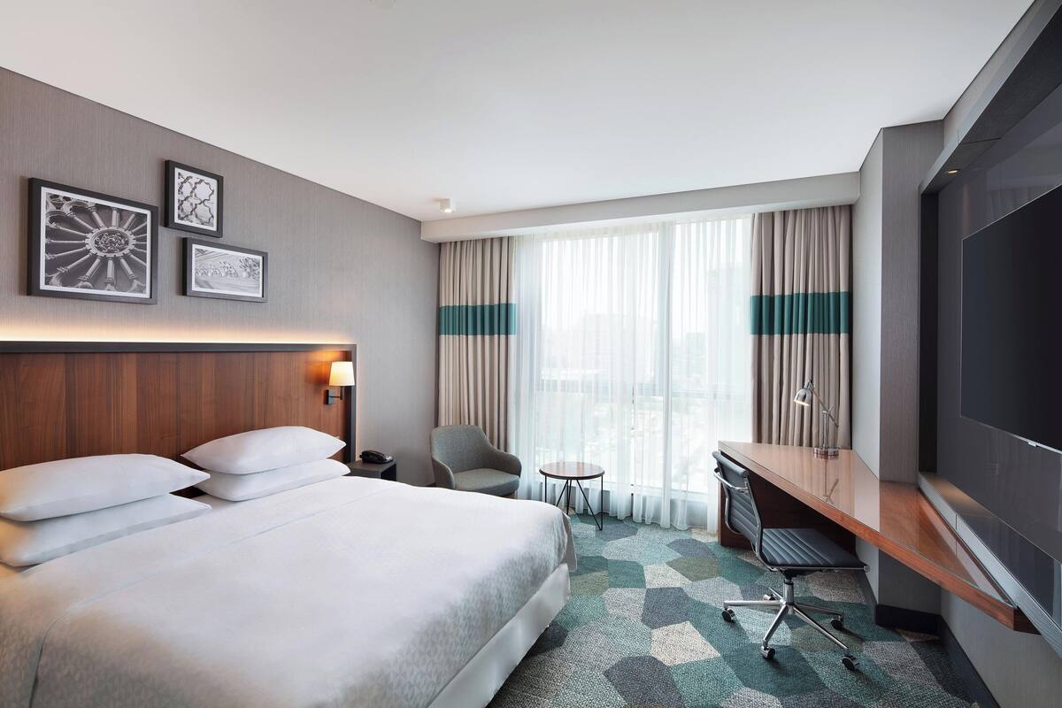 Una habitación de hotel con una cama grande, un escritorio, una silla y un televisor.