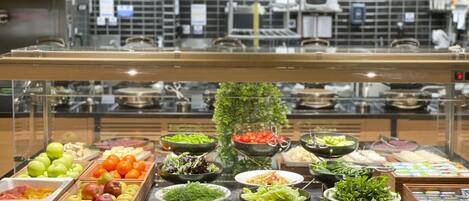 A buffet with various food items including fruits, vegetables, and salads.