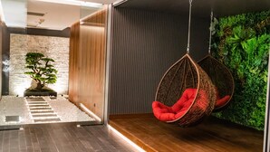 A modern interior with a hanging chair, a staircase, and a green wall with plants. - Four Points by Sheraton Istanbul Kagithane (Istanbul)