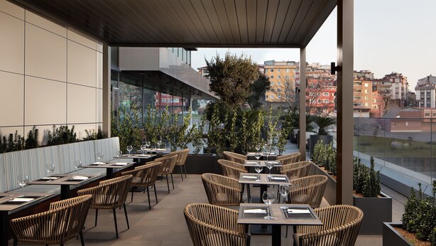An outdoor dining area with wicker chairs and tables, overlooking a cityscape. - Four Points by Sheraton Istanbul Kagithane (Istanbul)