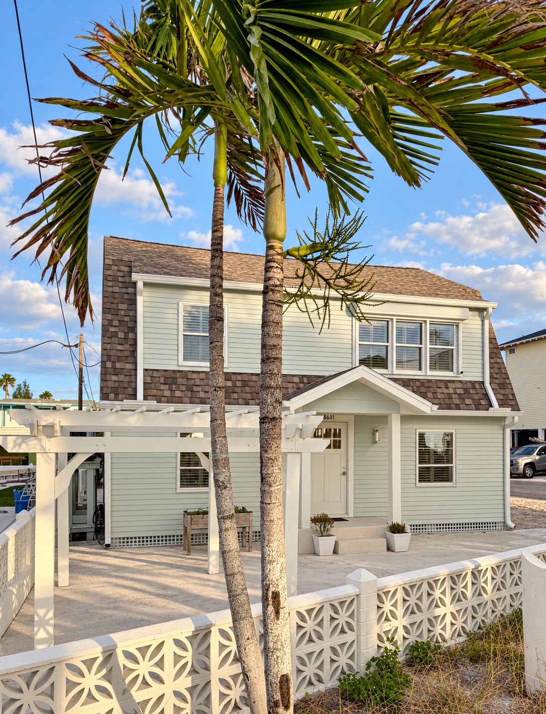 A two-story house with a front porch, a garage, and a palm tree.
