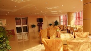 A hotel lobby with a large reception desk, seating area with patterned chairs, and a television mounted on the wall. - Greentree Inn Dezhou Kangbo Avenue Statium Express Hotel (Dezhou)