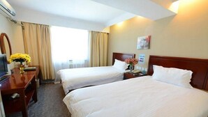 A hotel room with two single beds, a desk with a chair, a TV, and a vase with yellow flowers. - Greentree Inn Dezhou Kangbo Avenue Statium Express Hotel (Dezhou)