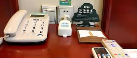Ein Hotelrezeptionstresen mit Telefon, Taschentuchspender, Notizblock und Fernbedienung.