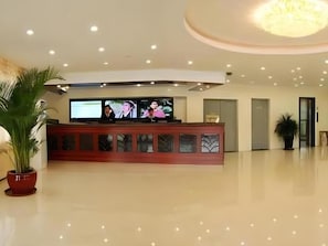A reception area with a reception desk, a television screen, and a potted plant. - Greentree Inn Tangshan Yuhua Road (Tangshan)