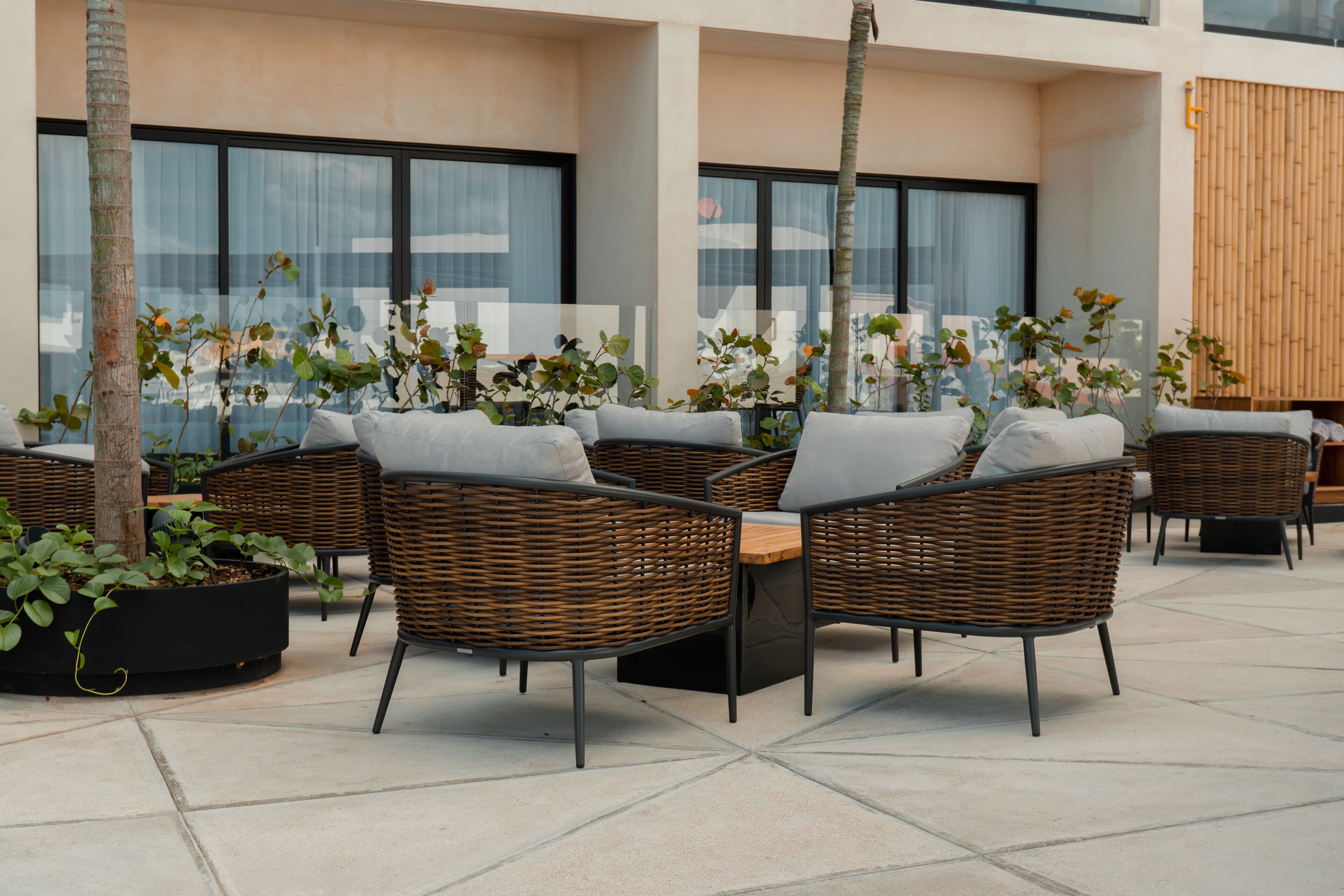 Een terras met rieten meubilair en planten in potten.