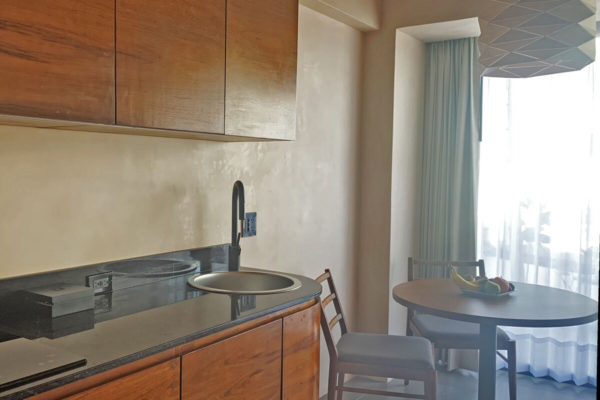 A modern kitchen with a black countertop, wooden cabinets, a sink, and a dining area with a table and chairs.