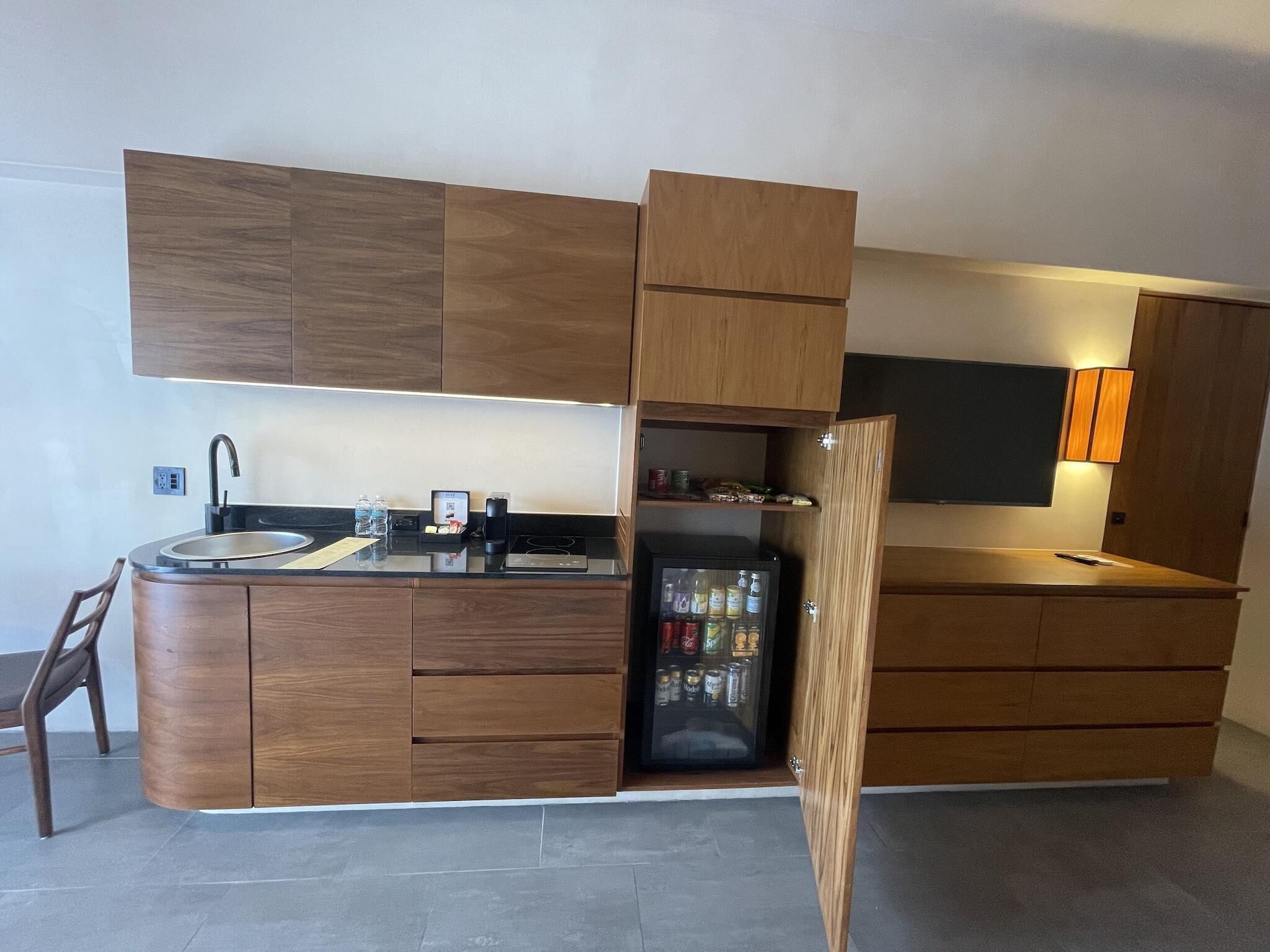 A modern kitchen with wooden cabinetry, a built-in sink, a refrigerator, and a small island with a coffee machine.