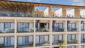 Un hôtel à plusieurs étages doté de balcons, de grandes fenêtres et d’espaces extérieurs aménagés pour s’asseoir.