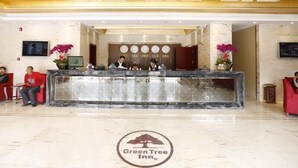 Ein Hotel-Empfangsbereich mit einer Marmor-Theke, einer Rezeption und dem Logo 'Green Tree Inn' auf dem Boden.