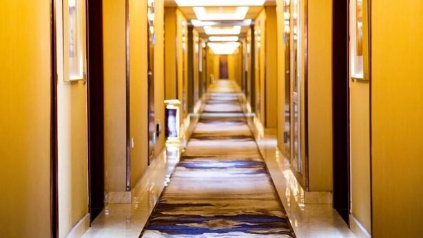 Ein Hotelgang mit Marmorboden und gelben Wänden.