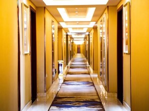 Un pasillo de hotel con piso de mármol y paredes amarillas.