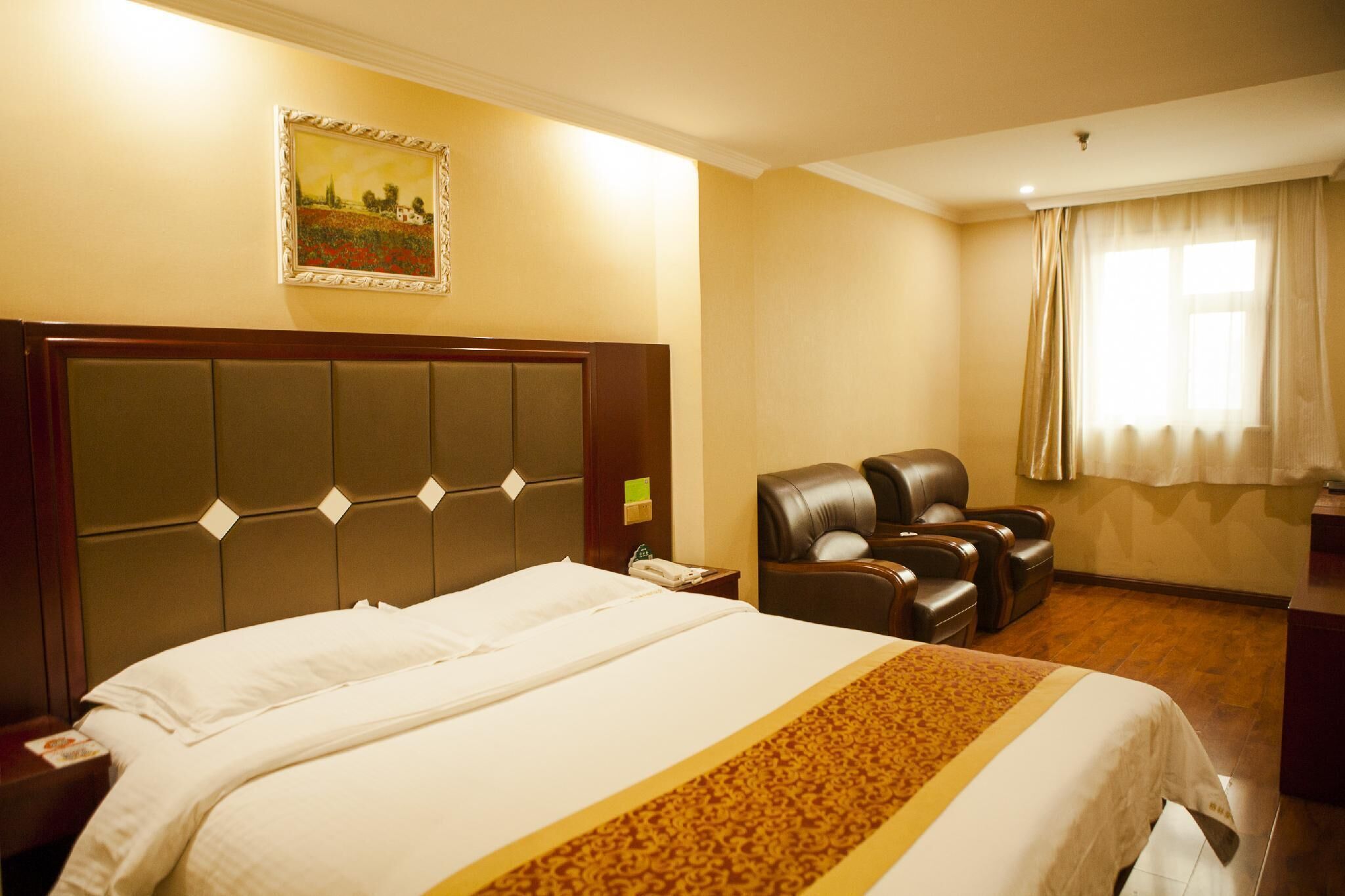 A hotel room with a large bed, a headboard with diamond-shaped lights, a massage chair, and a painting on the wall.