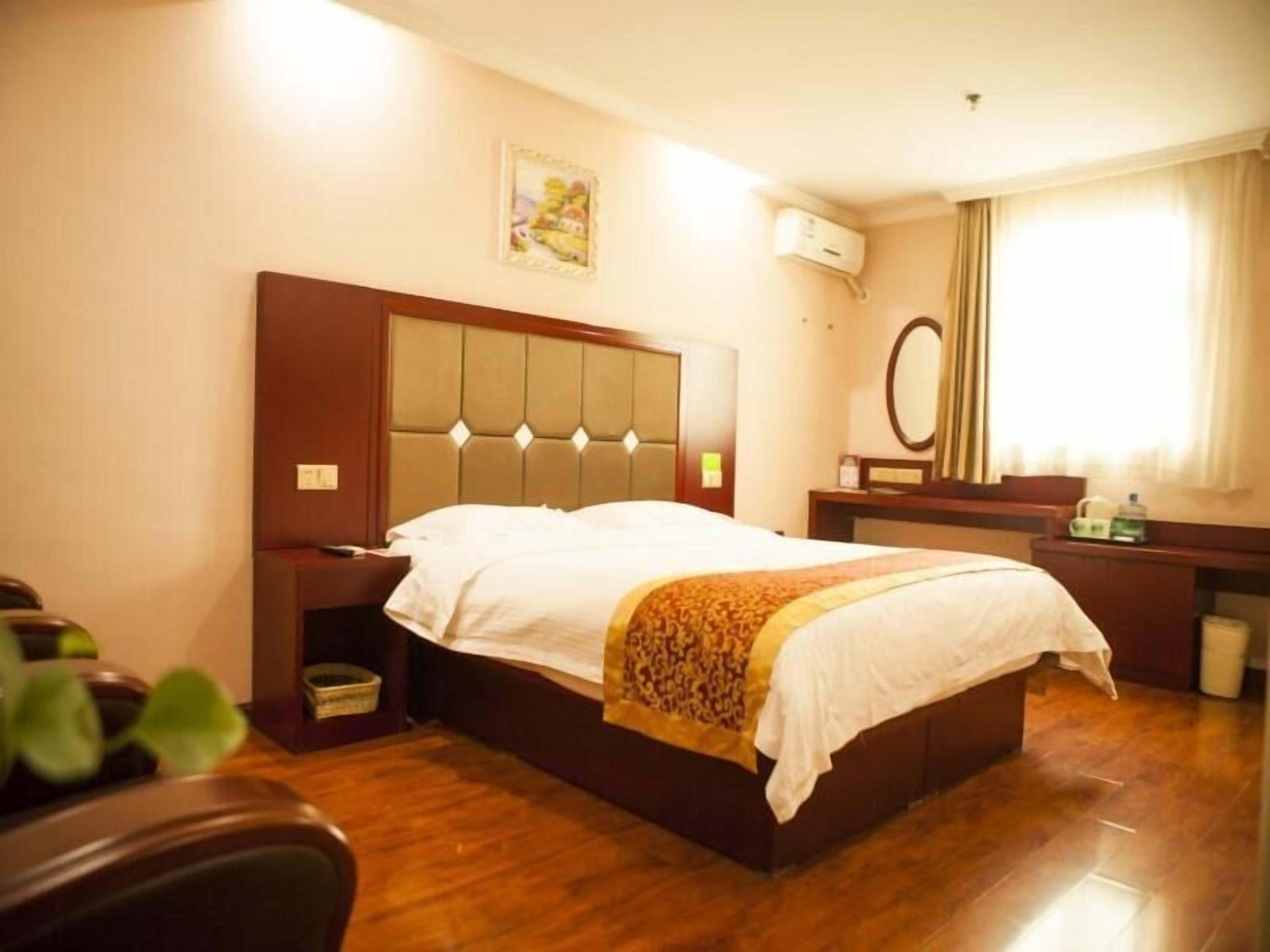 A hotel room with a large bed, a bedside table, a mirror, and a window with curtains.