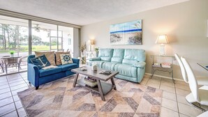 Ein Wohnzimmer mit einem blauen Sofa, einem Couchtisch und einem Bild von einer Strandlandschaft.