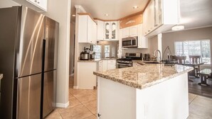 A modern kitchen with stainless steel appliances, white cabinetry, and a granite countertop island. - Spacious Retreat with 2 Master Suites, Foosball & AC (Flagstaff)