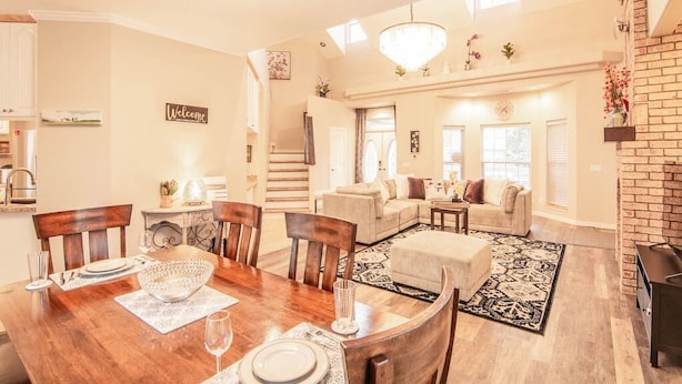 A spacious living area with a wooden dining table, a sofa, and a fireplace. - Spacious Retreat with 2 Master Suites, Foosball & AC (Flagstaff)